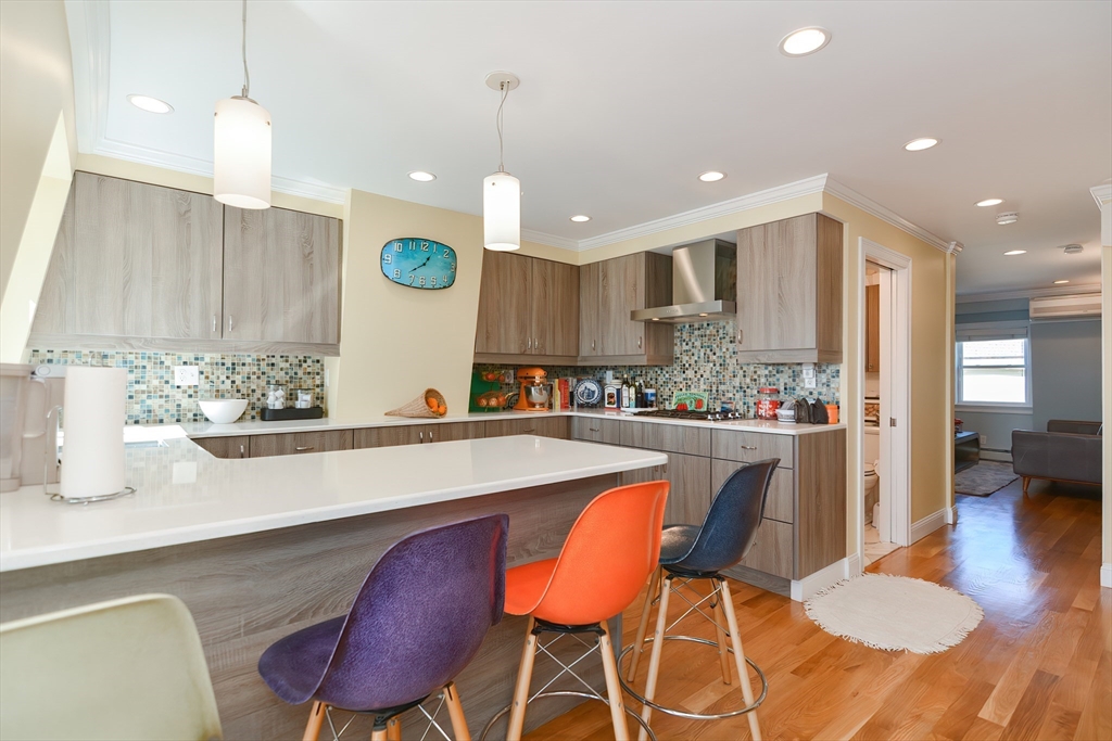 269 Webster Street, Unit 4 Boston, MA 02128 - Photo 6 of 36 a kitchen with stainless steel appliances kitchen island granite countertop a table chairs sink and microwave