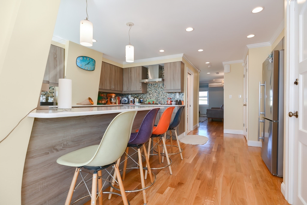 269 Webster Street, Unit 4 Boston, MA 02128 - Photo 8 of 36 a kitchen with stainless steel appliances kitchen island granite countertop a table chairs and a refrigerator