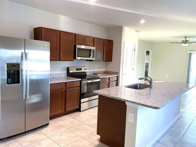 a kitchen with kitchen island granite countertop a sink dishwasher stove and refrigerator