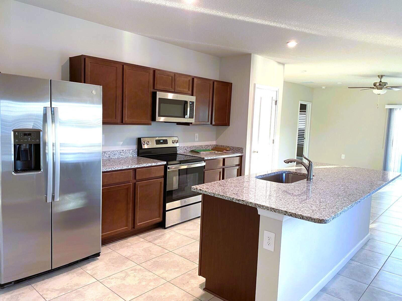 106 Pummelo Place Fort Pierce, FL 34981 - Photo 3 of 27 a kitchen with kitchen island granite countertop a sink dishwasher stove and refrigerator