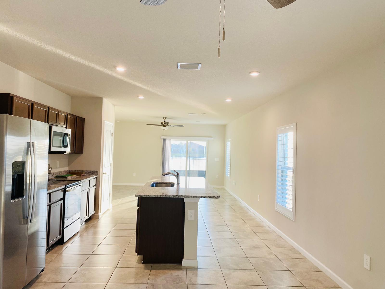 106 Pummelo Place Fort Pierce, FL 34981 - Photo 5 of 27 a kitchen with stainless steel appliances kitchen island granite countertop a refrigerator a stove and a sink