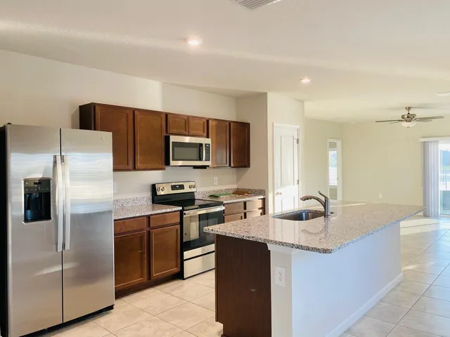 a kitchen with stainless steel appliances granite countertop a sink a stove a refrigerator a washer dryer and white cabinets