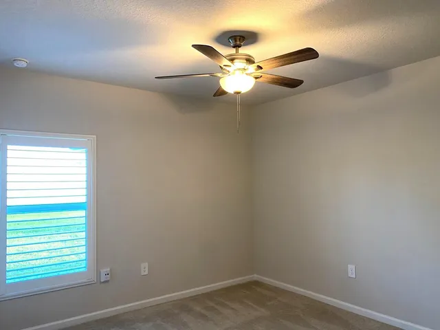 an empty room with windows and fan