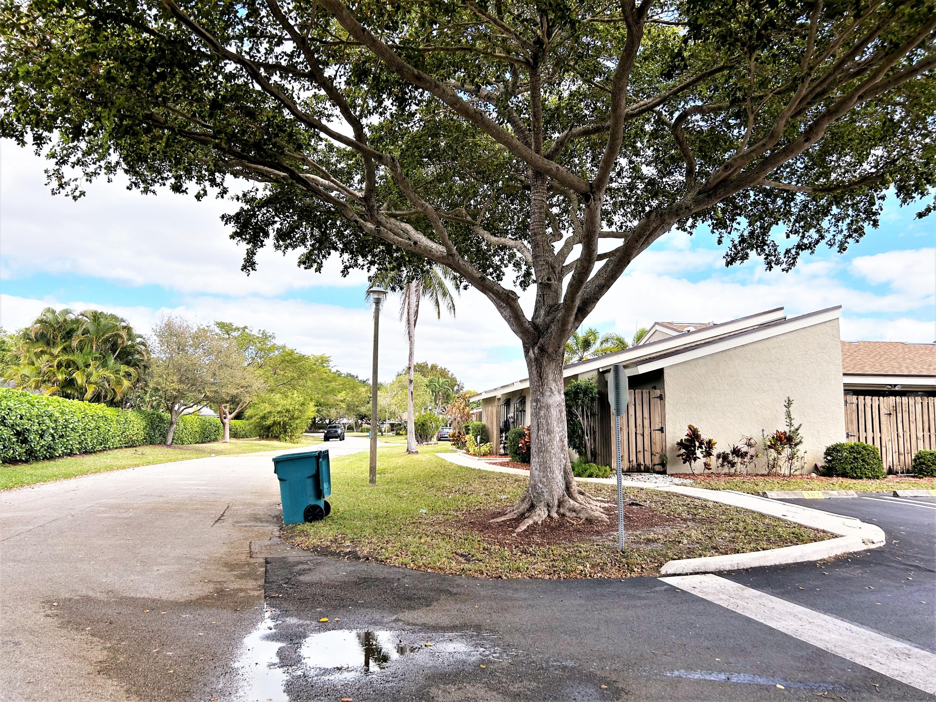 201 Meadows Drive Boynton Beach, FL 33436 - Photo 34 of 40 a view of a white house next to a yard with big trees