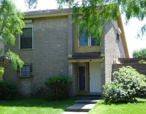 a view of a house with brick walls and a yard with plants