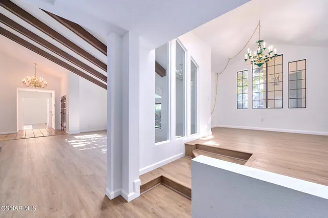 a view of an empty room with wooden floor and a ceiling fan