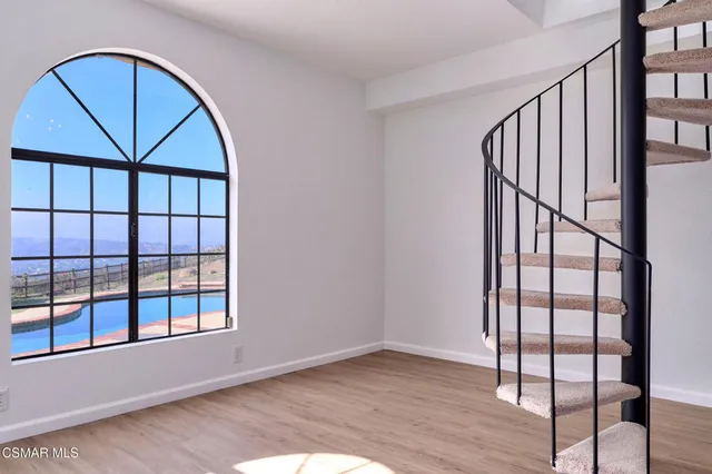 an empty room with wooden floor fireplace windows and cabinet
