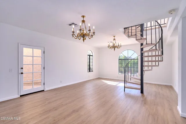 a view of an empty room with wooden floor fireplace and a window