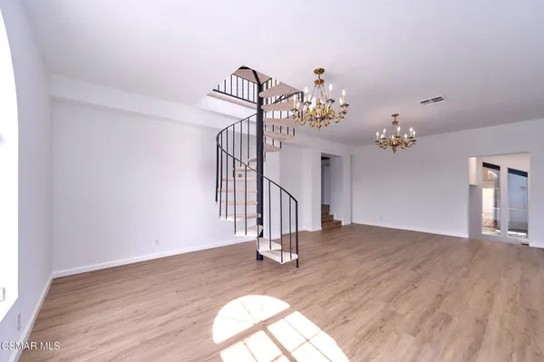 an empty room with wooden floor fireplace windows and cabinet