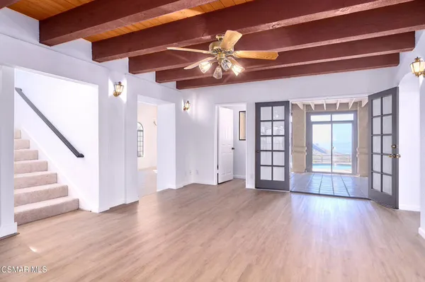 a view of an empty room with wooden floor fireplace and a window