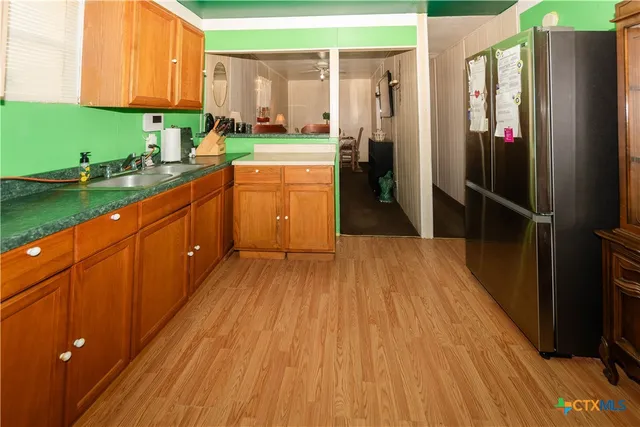 a kitchen with stainless steel appliances granite countertop a refrigerator a sink dishwasher and wooden cabinets with wooden floor