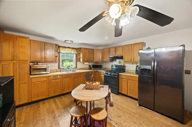 a kitchen with stainless steel appliances granite countertop a refrigerator a stove a sink dishwasher a dining table and chairs with wooden floor