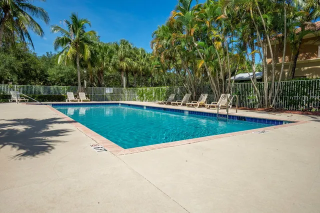 a view of a swimming pool with a yard and palm trees
