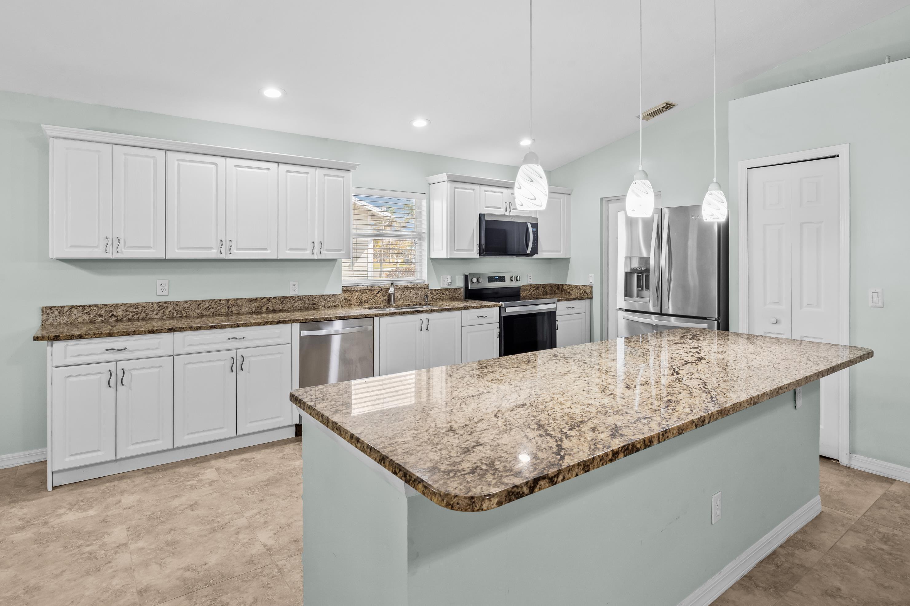 5925 Foxtail Way Fort Pierce, FL 34982 - Photo 6 of 29 a kitchen with stainless steel appliances granite countertop a sink stove and refrigerator