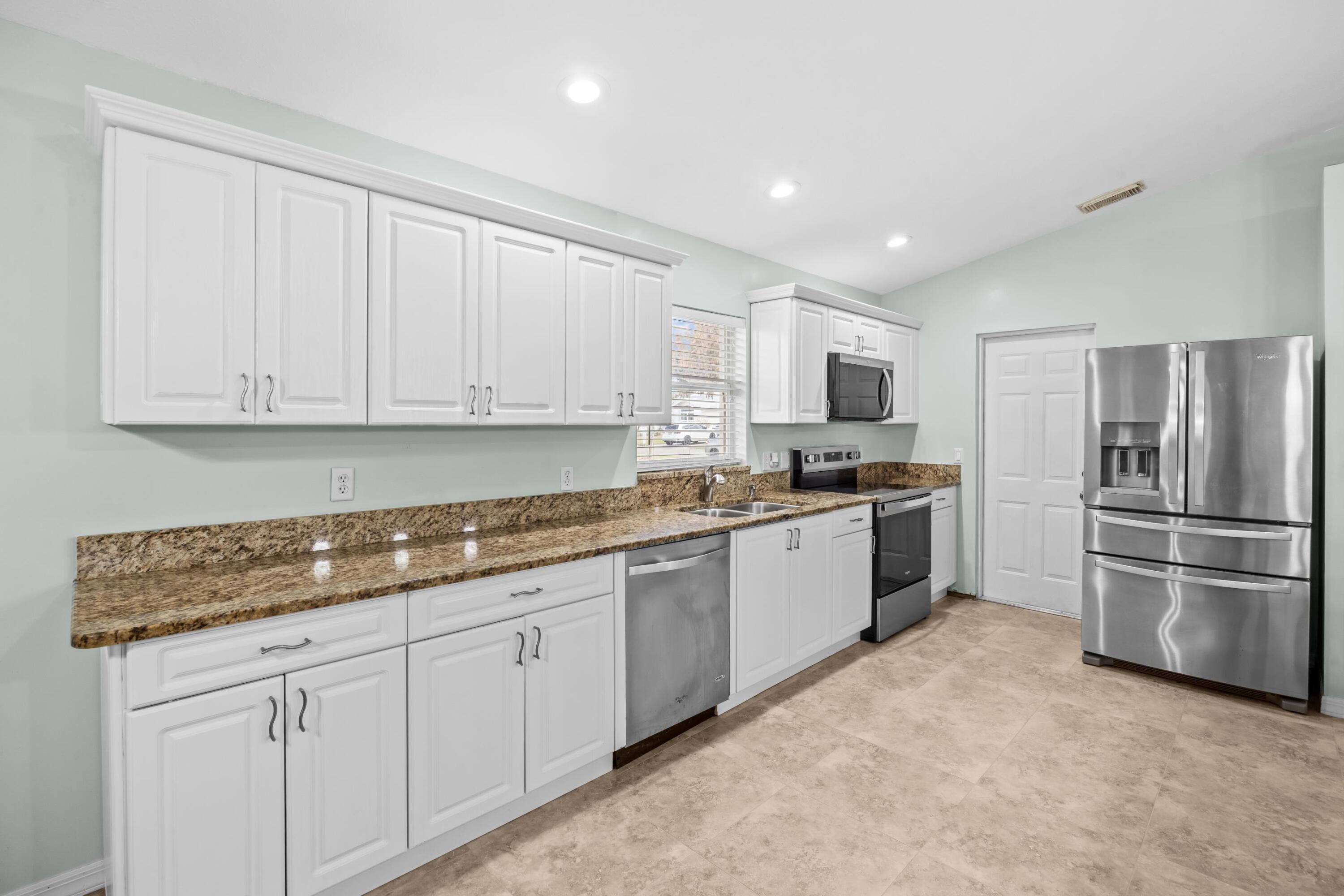 5925 Foxtail Way Fort Pierce, FL 34982 - Photo 9 of 29 a kitchen with granite countertop white cabinets and stainless steel appliances