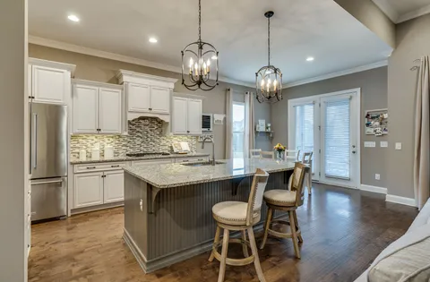 a kitchen with stainless steel appliances granite countertop a sink dishwasher a dining table and chairs with wooden floor