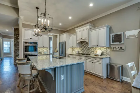 a kitchen with stainless steel appliances granite countertop a kitchen island hardwood floor sink stove dining table and chairs