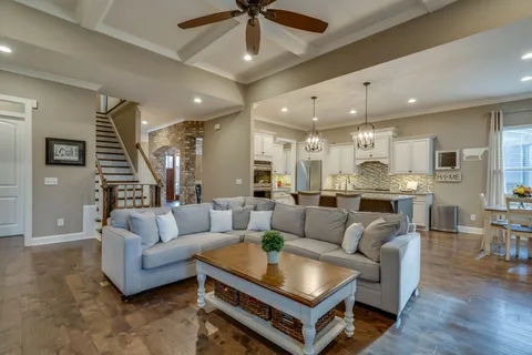 a living room with furniture kitchen view and a chandelier