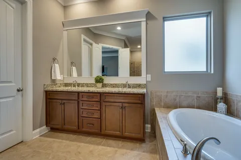 a bathroom with a granite countertop tub sink and mirror