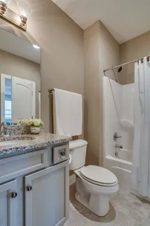 a bathroom with a granite countertop toilet sink and mirror