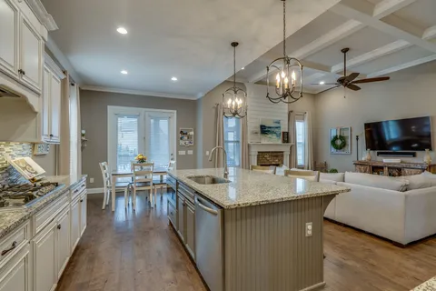 a open kitchen with stainless steel appliances granite countertop stove a table and chairs in it