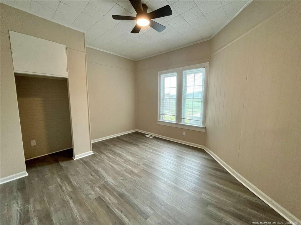 416 Old Maxton Road Raeford, NC 28376 - Photo 7 of 26 an empty room with wooden floor chandelier fan and windows