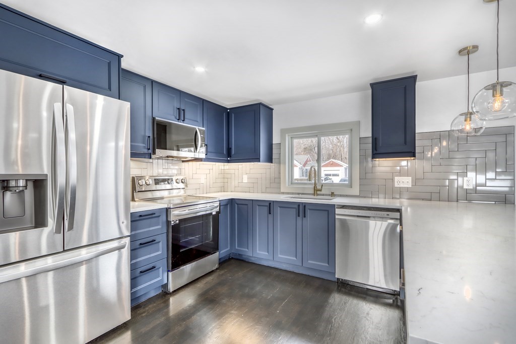 11 Spring Lane Saugus, MA 01906 - Photo 7 of 31 a kitchen with stainless steel appliances granite countertop a refrigerator a stove a sink dishwasher a microwave oven with cabinets and wooden floor