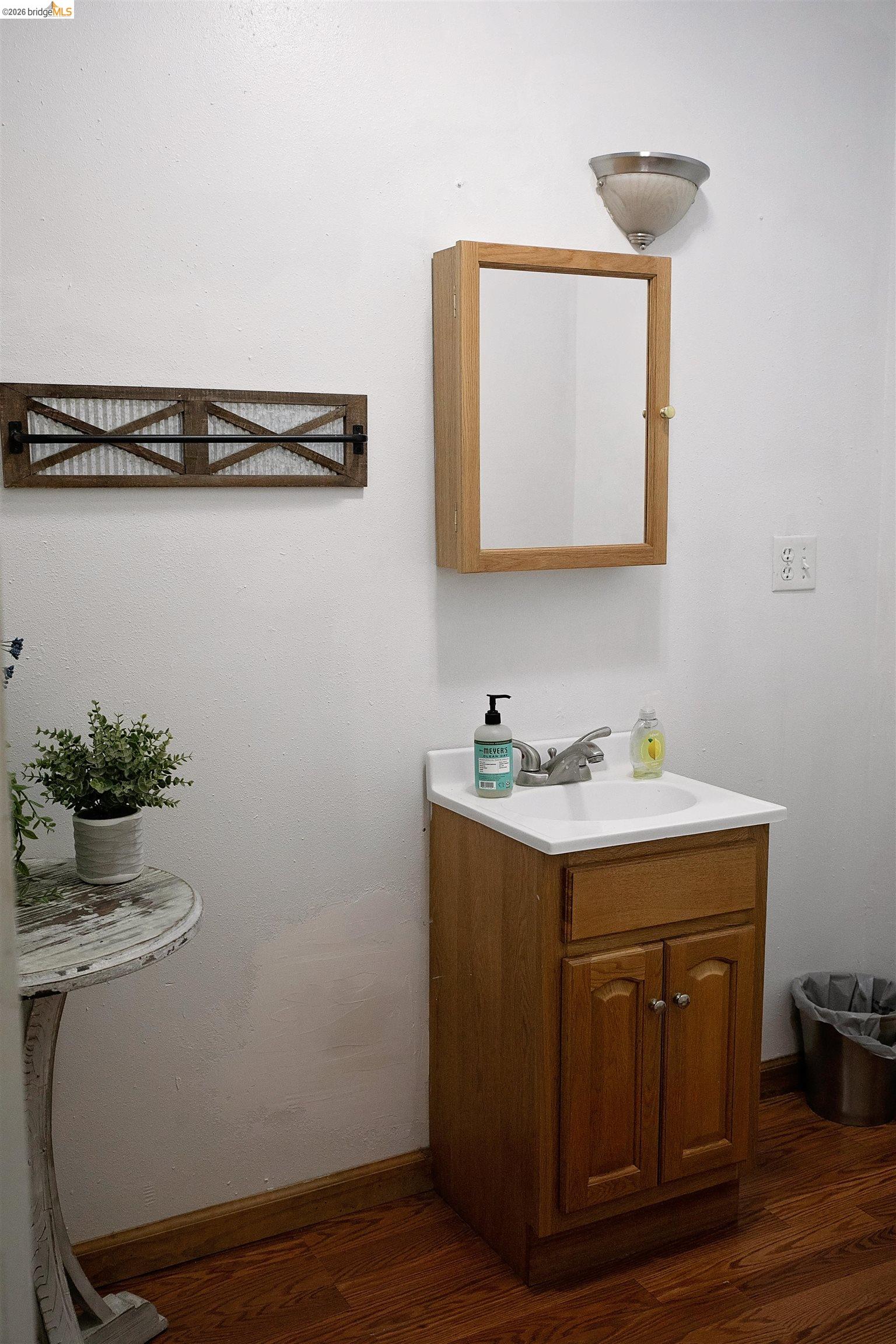 20982 Shaws Flat Road Sonora, CA 95370 - Photo 18 of 26 Bathroom vanity with a white countertop and integrated sink, accompanied by a wood-finish medicine cabinet and wall-mounted light fixture