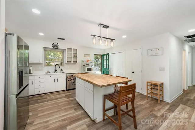 a kitchen with a stove a sink dishwasher and a refrigerator with wooden floor