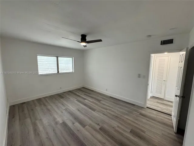 a view of a room with wooden floor a ceiling fan and window