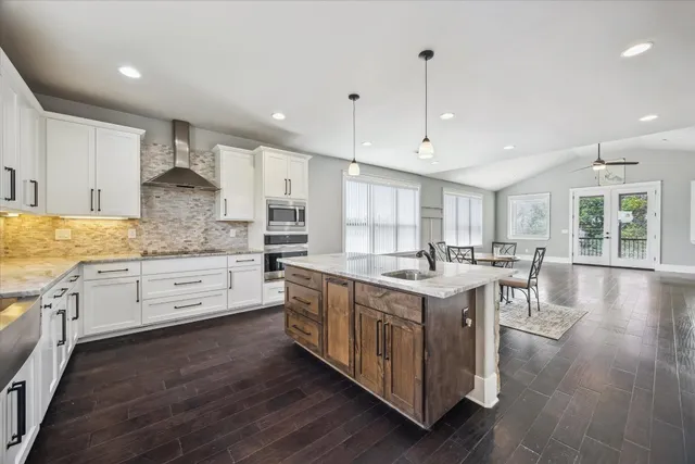 a kitchen with stainless steel appliances granite countertop table chairs and wooden floor