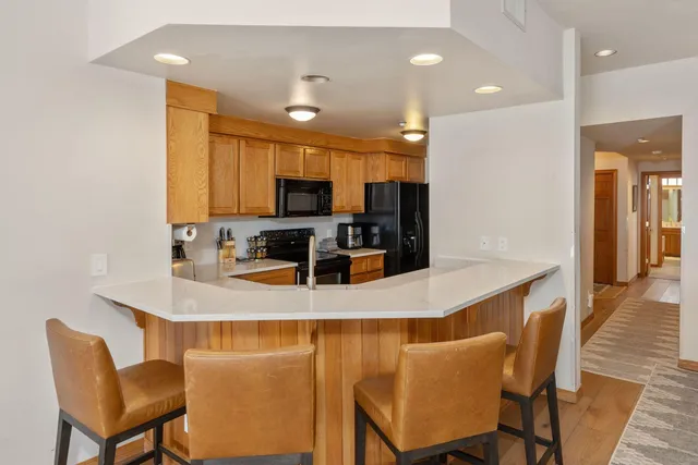a kitchen with stainless steel appliances a dining table chairs refrigerator and microwave