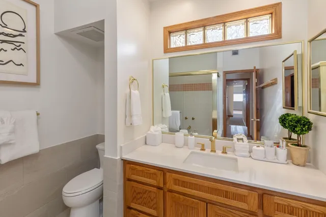 a bathroom with a granite countertop sink a toilet a mirror and shower
