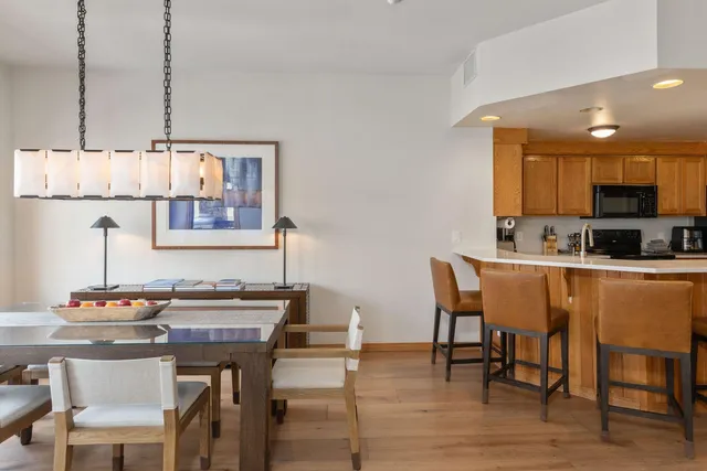 a kitchen with stainless steel appliances granite countertop a sink a stove a kitchen island with chairs and wooden floor