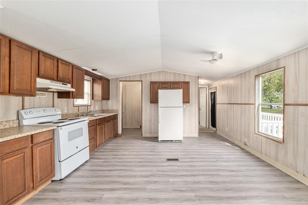 8535 Southwest 155th Street Dunnellon, FL 34432 - Photo 11 of 35 a large kitchen with a refrigerator a stove top oven a sink dishwasher and white cabinets with wooden floor