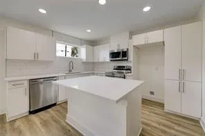 a kitchen with kitchen island a white counter top space cabinets and stainless steel appliances