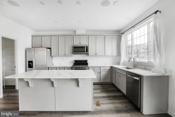 a kitchen with stainless steel appliances granite countertop a refrigerator a sink a stove a microwave and island