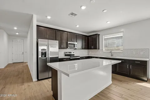 a kitchen with stainless steel appliances granite countertop a refrigerator a sink dishwasher a stove and white countertops with wooden floor