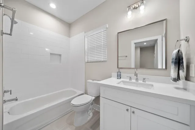 a bathroom with a toilet a sink a mirror a bathtub and vanity