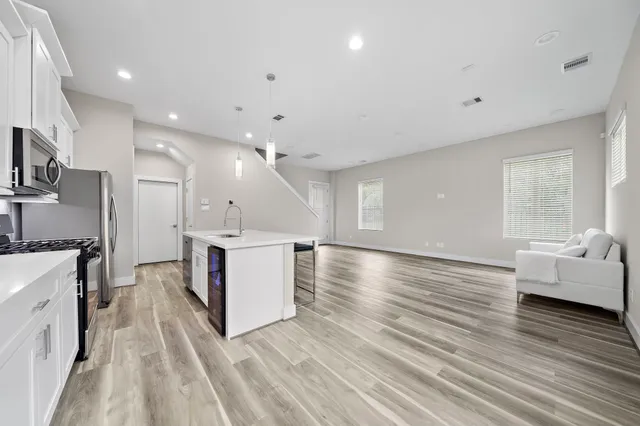 a large white kitchen with a large window and stainless steel appliances