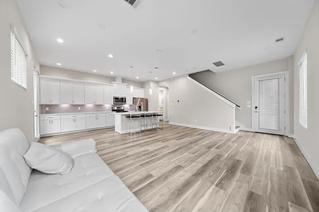 a large white room with kitchen island and stainless steel appliances