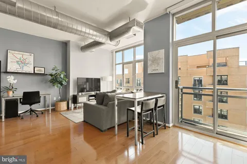 a living room with furniture large window and wooden floor