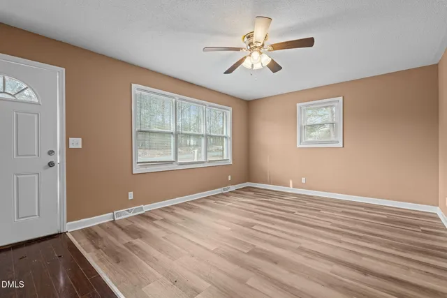 a view of an empty room with window and a chandelier fan