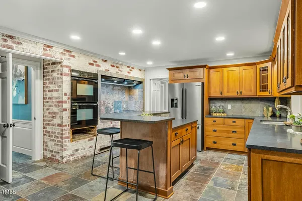 a kitchen with stainless steel appliances granite countertop a refrigerator a sink dishwasher a stove and white cabinets with wooden floor