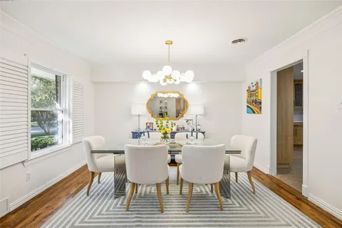 a dining room with wooden floor a chandelier a glass table and chairs
