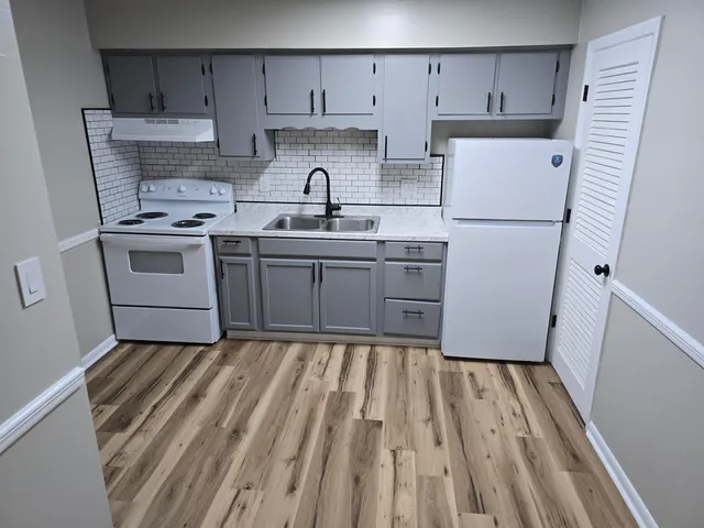 a kitchen with sink a refrigerator and white cabinets