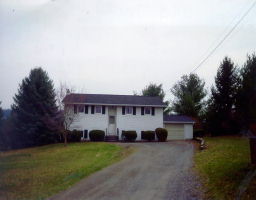 a view of a house with a big yard and large trees