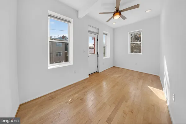 a view of empty room with wooden floor and ceiling fan