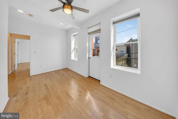 a view of empty room with wooden floor and ceiling fan