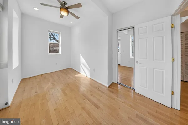 an empty room with wooden floor chandelier fan and windows